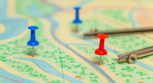 A paper map with 3 pins at different points on the map.